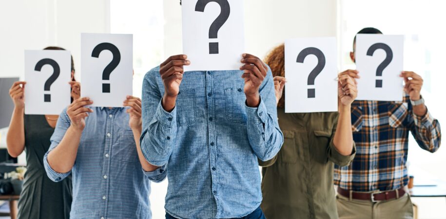 A group of people holding a question-mark sign on their faces